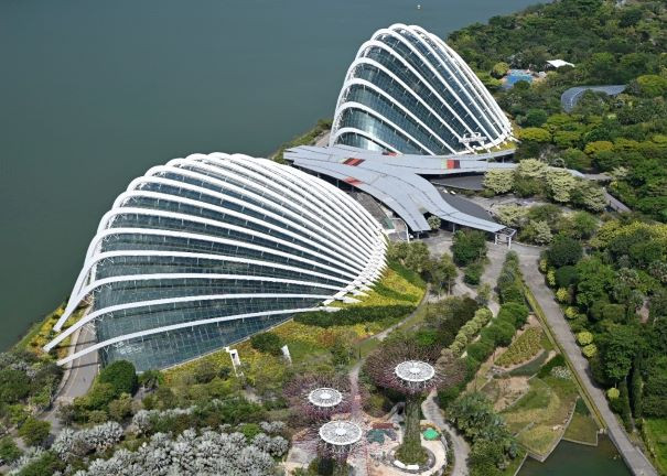 Twin shell-shaped conservatory domes in gardens by the water